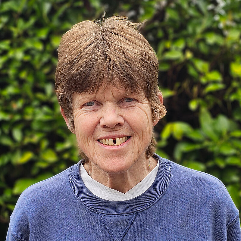 Annabel Hennessy smiling. She is standing in front of a green hedge.