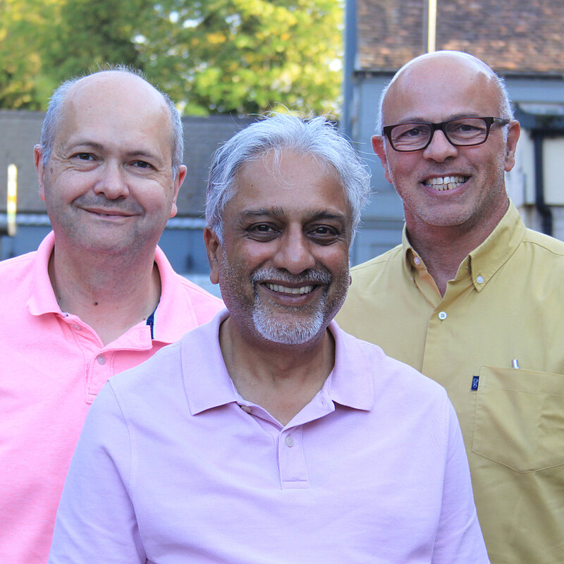 The smiling Bushey Park ward team of Maxie Allen, Shailain Shah and Marc Amron are standing together in pastel coloured shirts.